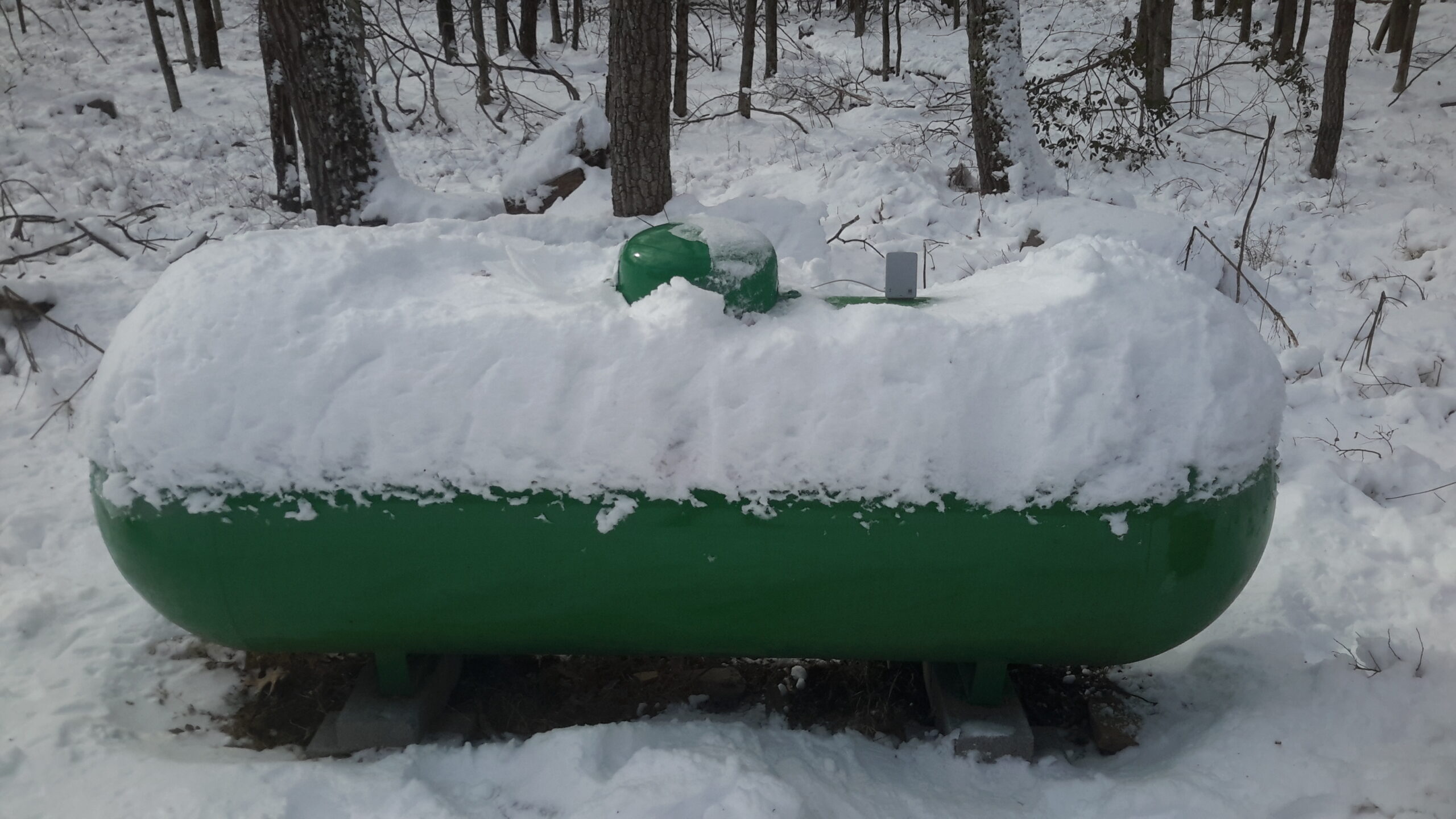 Snow covered green propane tank